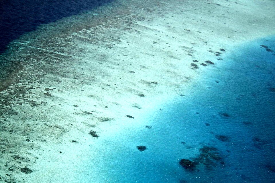 An aerial view of turquoise water and a reef in the Maldives
